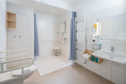 ein weißes Bad mit einem Waschbecken und einer Dusche in der Unterkunft Strandhotel Gerken in Wangerooge