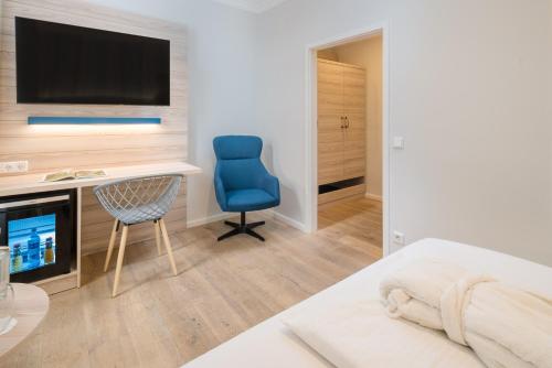 a bedroom with a bed and a desk and a blue chair at Strandhotel Gerken in Wangerooge