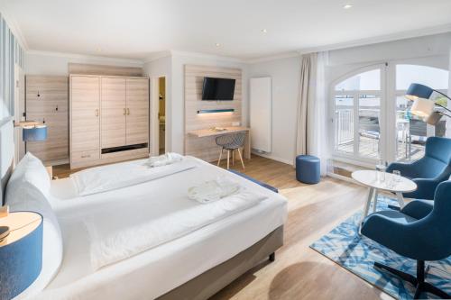 a bedroom with a bed and a desk and a chair at Strandhotel Gerken in Wangerooge