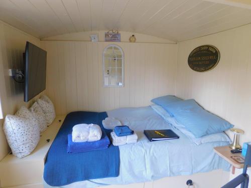 um quarto com uma cama com almofadas azuis e um livro em annes hatch hut 