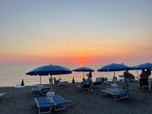 a group of people sitting on the beach under umbrellas at Lido Tirreno beach in Campora San Giovanni