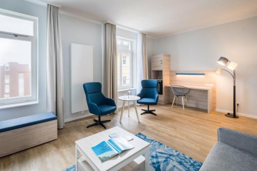 a living room with two blue chairs and a couch at Strandhotel Gerken in Wangerooge