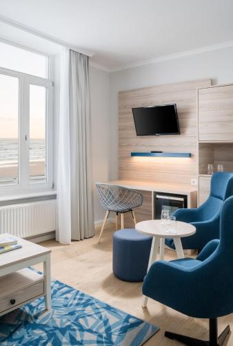 a living room with two blue chairs and a table at Strandhotel Gerken in Wangerooge