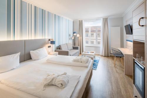 a hotel room with two beds and a chair at Strandhotel Gerken in Wangerooge