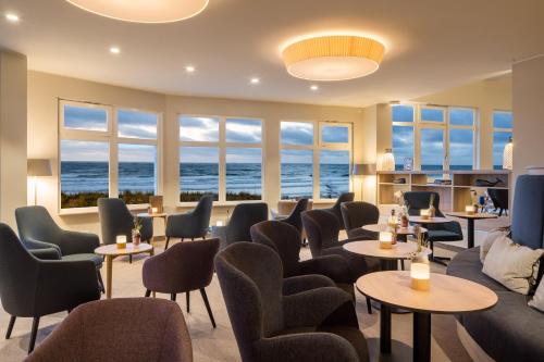 a waiting room with tables and chairs and the ocean at Strandhotel Gerken in Wangerooge