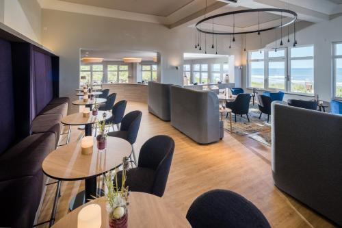 a restaurant with tables and chairs and windows at Strandhotel Gerken in Wangerooge