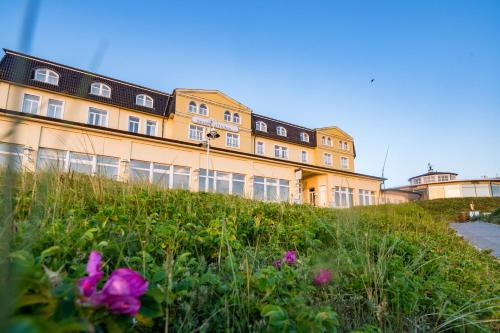 a building on top of a hill with flowers at Strandhotel Gerken in Wangerooge