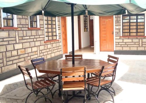 un tavolo in legno e sedie sotto un ombrellone di Aster Suites Kisumu a Awasi