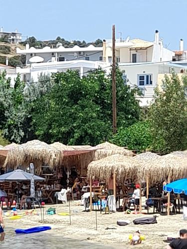 een strand met tafels en rieten parasols en stoelen bij Kate House in Áyioi Apóstoloi