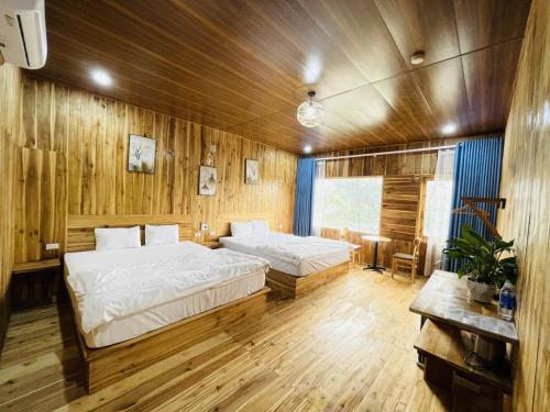 two beds in a room with wooden walls and wooden floors at Tuyet's hostel in Ninh Binh