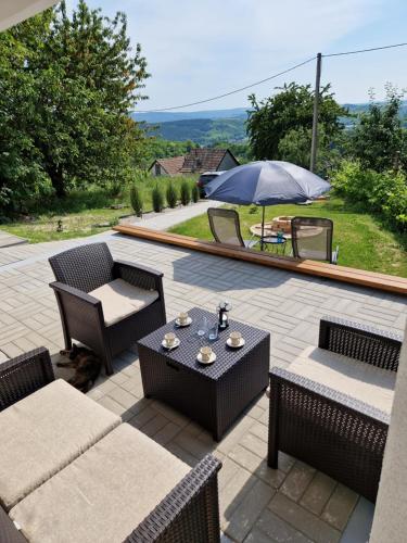 a patio with a table and chairs and an umbrella at Várta-Lak Panoráma Présház Vendégház in Bakonycsernye