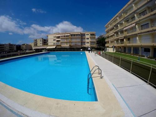 een groot blauw zwembad naast een gebouw bij Appartement climatisé avec piscines proche mer in Mandelieu-la-Napoule