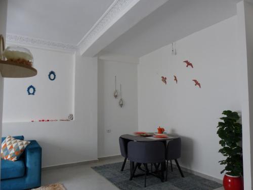een witte kamer met een tafel en een blauwe stoel bij EXCELLENT rapport Qualité Prix pour cet Appartement 3 étoiles Neuf 2P Tout Confort Résidence Golf Mesnana Tanger in Tanger