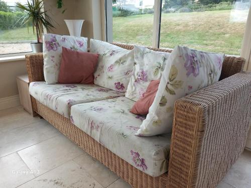 a wicker couch with pillows on it in front of a window at Safe Haven - Luxury Family Accommodation in Carlingford
