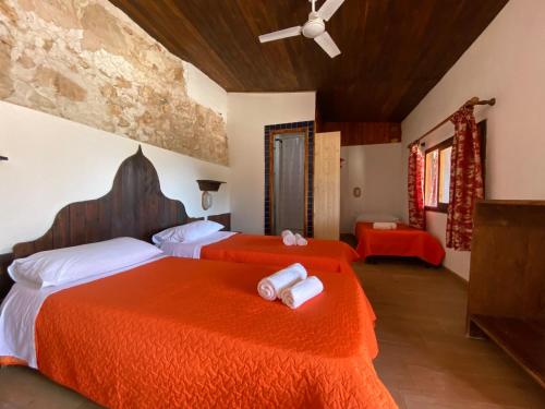 duas camas num quarto com lençóis vermelhos e toalhas brancas em Villaggio La Roccia camping em Lampedusa
