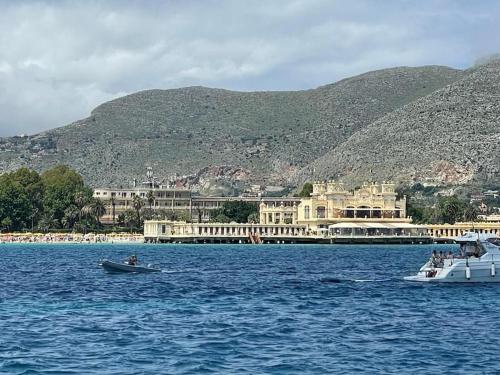 a large building in the middle of a body of water with a boat at La Scalinatella di Mondello in Palermo