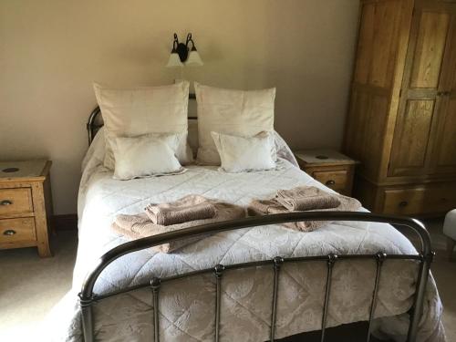a bedroom with a bed with white sheets and pillows at Owletts Barn B&B in Bodmin