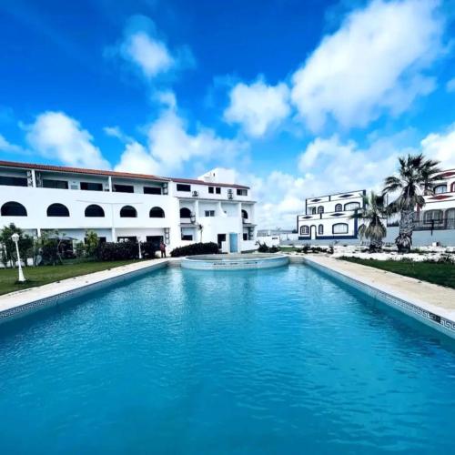 a swimming pool in front of a white building at Oásis de verão- 2 bedrooms flat with swimming pool in Sagres