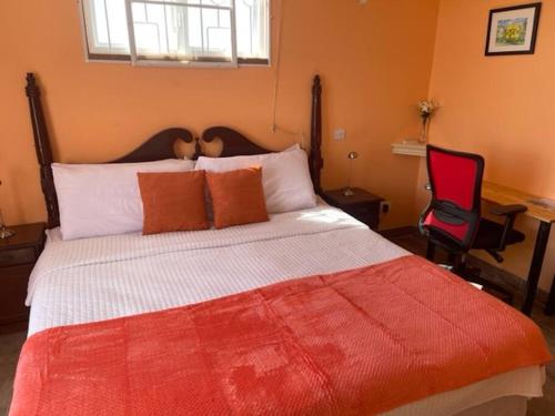 um quarto com uma cama grande e uma cadeira vermelha em Cottage: 7 minutes from airport! em Saint Philip