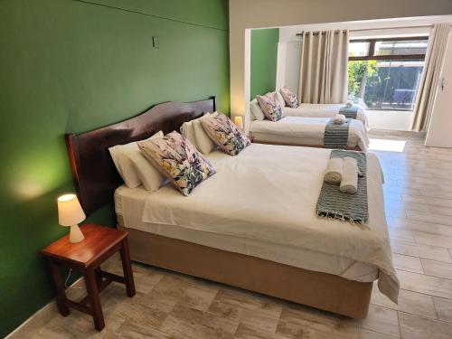 two beds in a room with green walls at Livingstone Lodge in Victoria Falls
