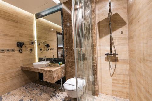 a bathroom with a shower and a toilet and a sink at Tura Hotel in Riyadh