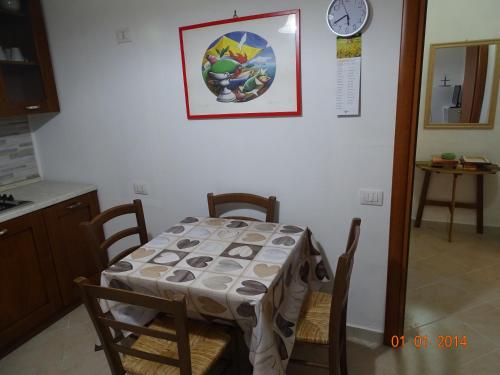 La SdrisciaにあるAgriturismo Oasisのテーブルと椅子付きのキッチン(壁掛け時計付)