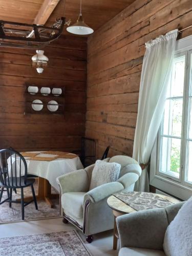 sala de estar con paredes de madera, mesa y sillas en Punainen pihatorppa Hauholla en Alvettula