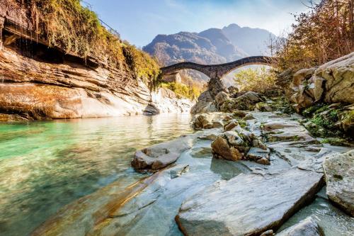 a bridge over a river next to a mountain at RELAX Camelia Apartment in Locarno