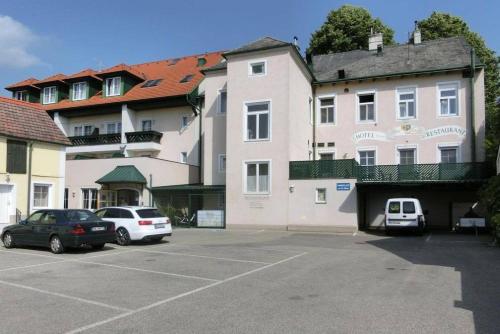 un estacionamiento con autos estacionados frente a un edificio en Self-Check-in Hotel VinoQ Mistelbach, en Mistelbach
