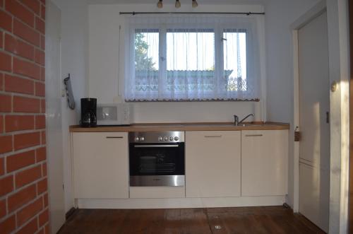 eine Küche mit weißen Schränken, einem Waschbecken und einem Fenster in der Unterkunft Seeblick Bungalow in Arendsee