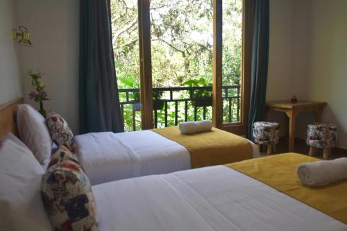 two beds in a hotel room with a window at Margarit Boutique Hotel in Mindo