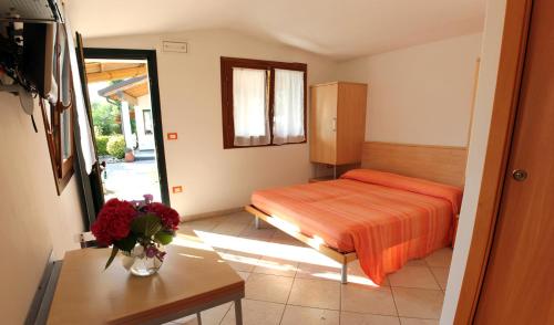 een slaapkamer met een bed en een vaas met bloemen op een tafel bij La Conchiglia in Chioggia