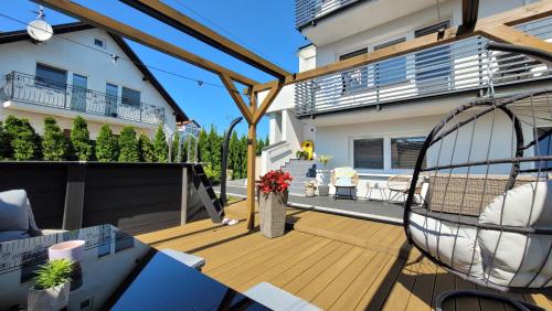 a deck with a swing and a house at GoldenApart Apartamenty- 2 sypialnie in Krynica Morska