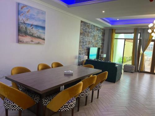 a dining room with a wooden table and chairs at Rose Beach Villas in Durat  Alarous