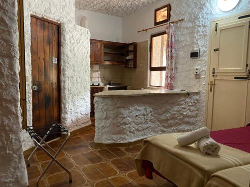 Villaggio La Roccia camping في لامبيدوسا: مطبخ بحائط حجري وطاولة فيه