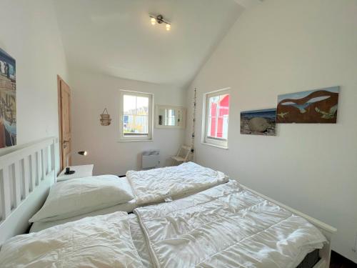 - un lit blanc dans une chambre avec 2 fenêtres dans l'établissement Strandpark Sierksdorf H049, à Sierksdorf
