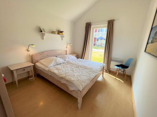 a bedroom with a bed and a window and a chair at Strandpark Sierksdorf H058 in Sierksdorf