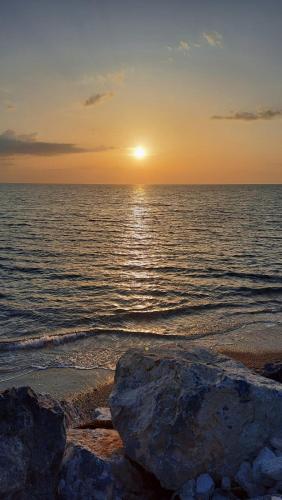 a sunset over the ocean with rocks on the beach at Lido Tirreno beach in Campora San Giovanni