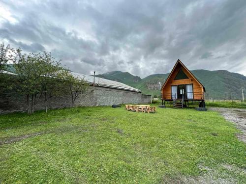 a house with a yard with a bench and a building at Thomas' Hut in Kazbegi