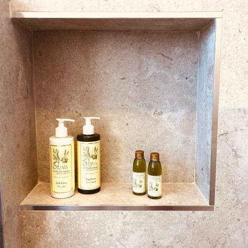 three bottles of soap sitting on a shelf at Il Borgo Boutique Rooms by KasaVacanze in Porto San Paolo