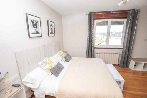 a bedroom with a white bed and a window at Pensión Lobre in O Pedrouzo