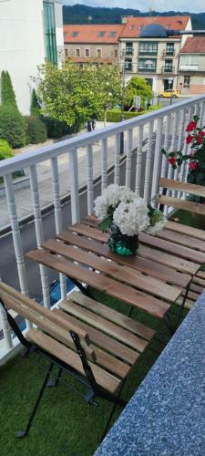 a wooden bench sitting on a balcony with flowers at Pensión Lobre in O Pedrouzo