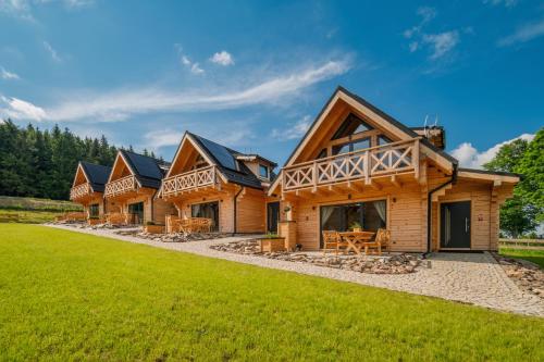 a row of log homes with a green lawn at Domki Osada Zieleniec in Duszniki Zdrój