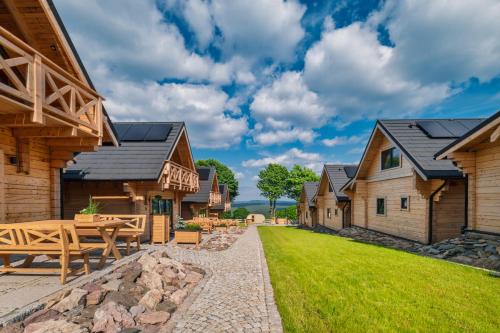 einen Hinterhof mit Holzgebäuden und einem Steinweg in der Unterkunft Domki Osada Zieleniec in Duszniki-Zdrój