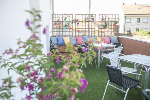 a patio with a couch and tables and chairs at Pensión Lobre in O Pedrouzo