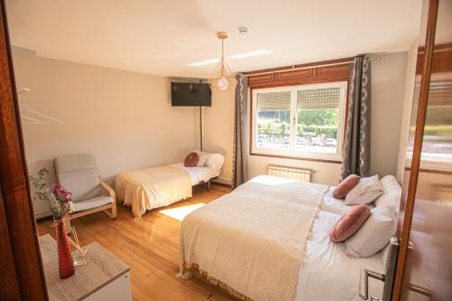 a bedroom with two beds and a window at Pensión Lobre in O Pedrouzo