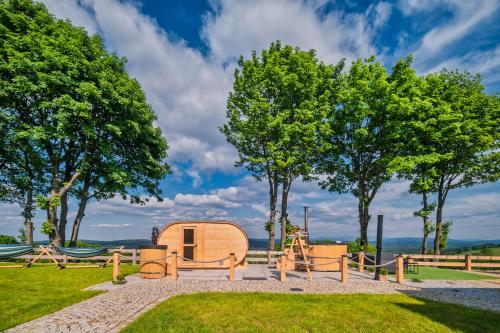 a cabin in a park with trees and a playground at Domki Osada Zieleniec in Duszniki Zdrój