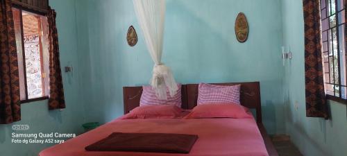 Bett mit rosa Bettwäsche und Kissen in einem Zimmer in der Unterkunft Lawang Inn in Bukit Lawang