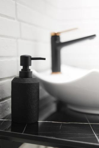 a black soap dispenser on a counter next to a sink at Sabbia Mini Pool Suites in Preveza