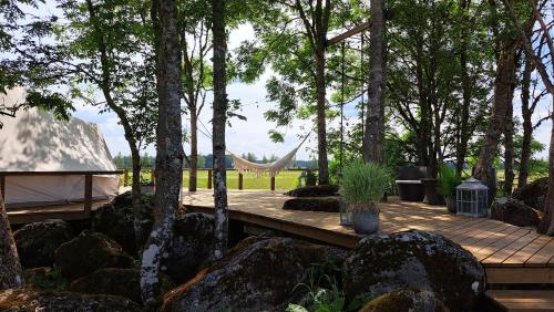 une terrasse en bois avec un hamac dans les arbres dans l'établissement Ohukotsu Glamping, 